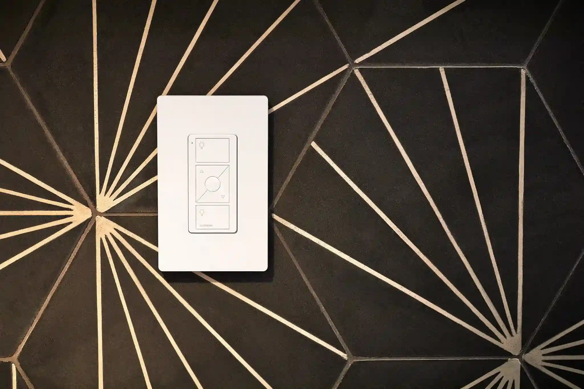 Controle Pico Lutron branco instalado em parede com revestimento preto e dourado